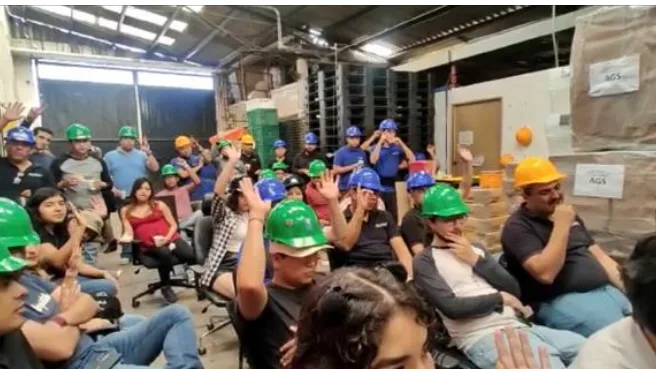 El público de la ponencia en la planta, con casco puesto y varias manos levantadas